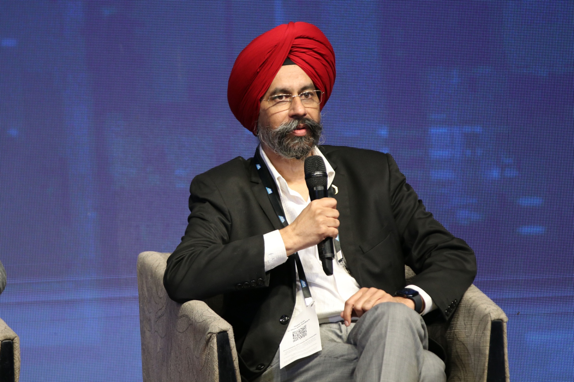 Ekjyot Chahal speaking on stage with microphone at a leadership panel